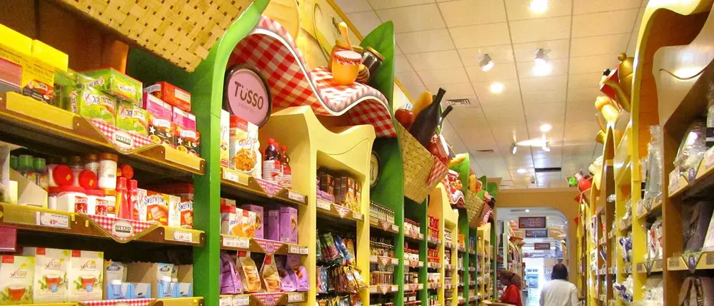 Hazi Hinam Rishon LeZion specialty food aisle with colorful custom shelving and oversized food-themed decorative elements.