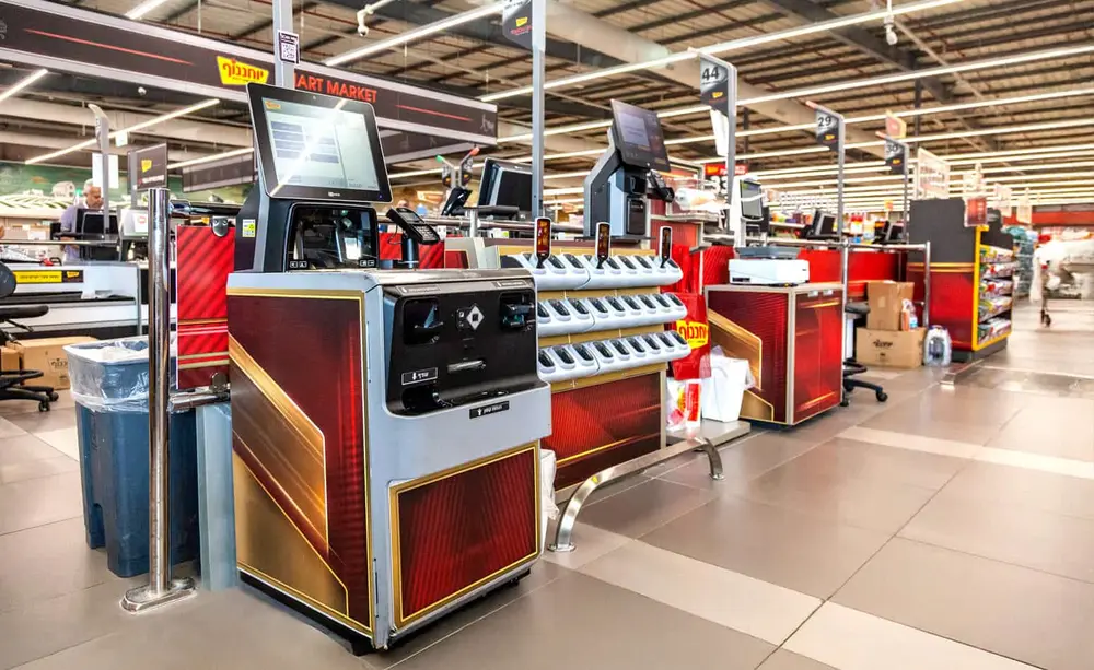 Yohananof Ashdod self-checkout station with custom red and gold branded design and handheld scanner terminals.